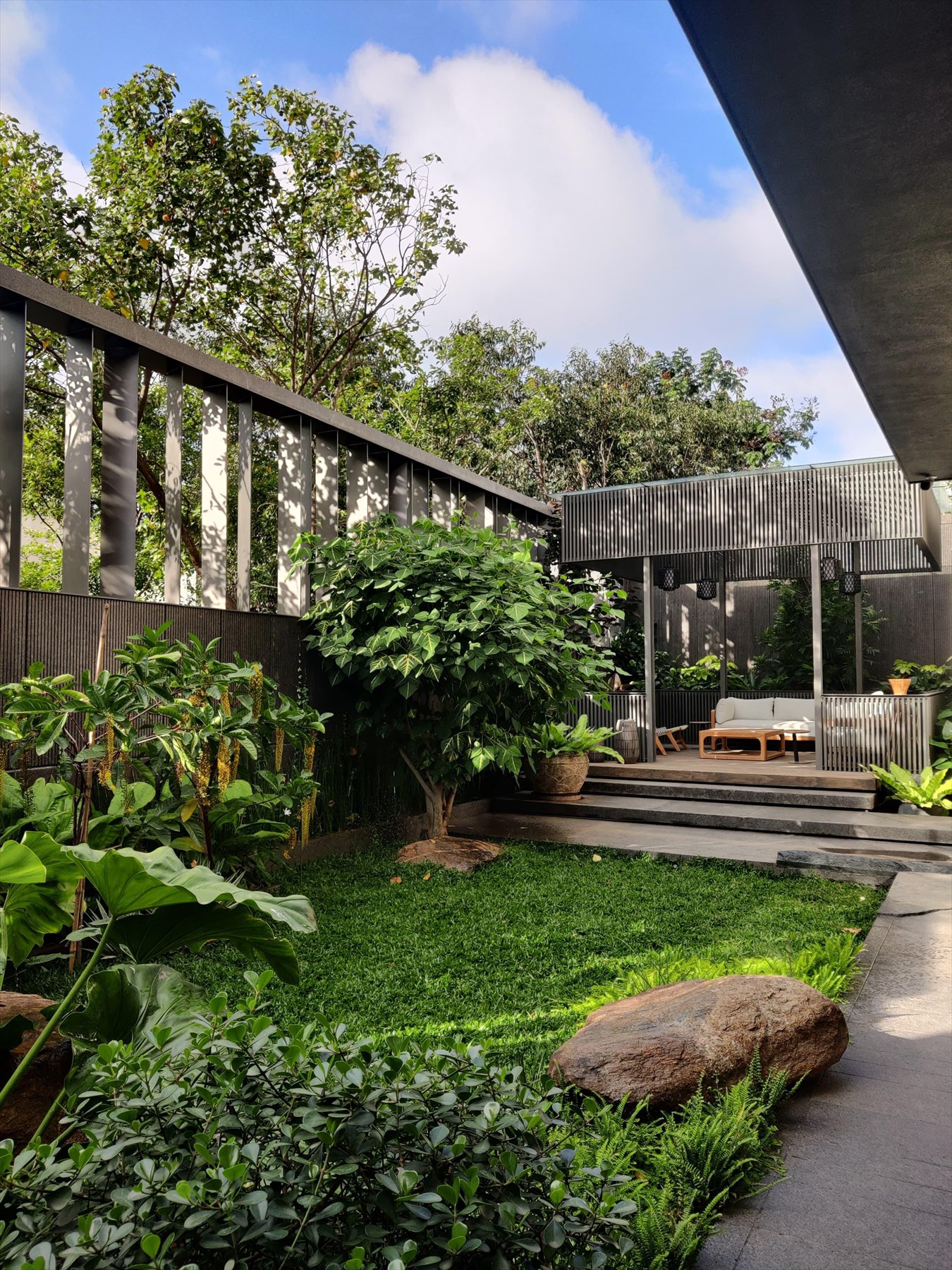 Garden court with a lawn, a boulder and a slatted pavilion lounge