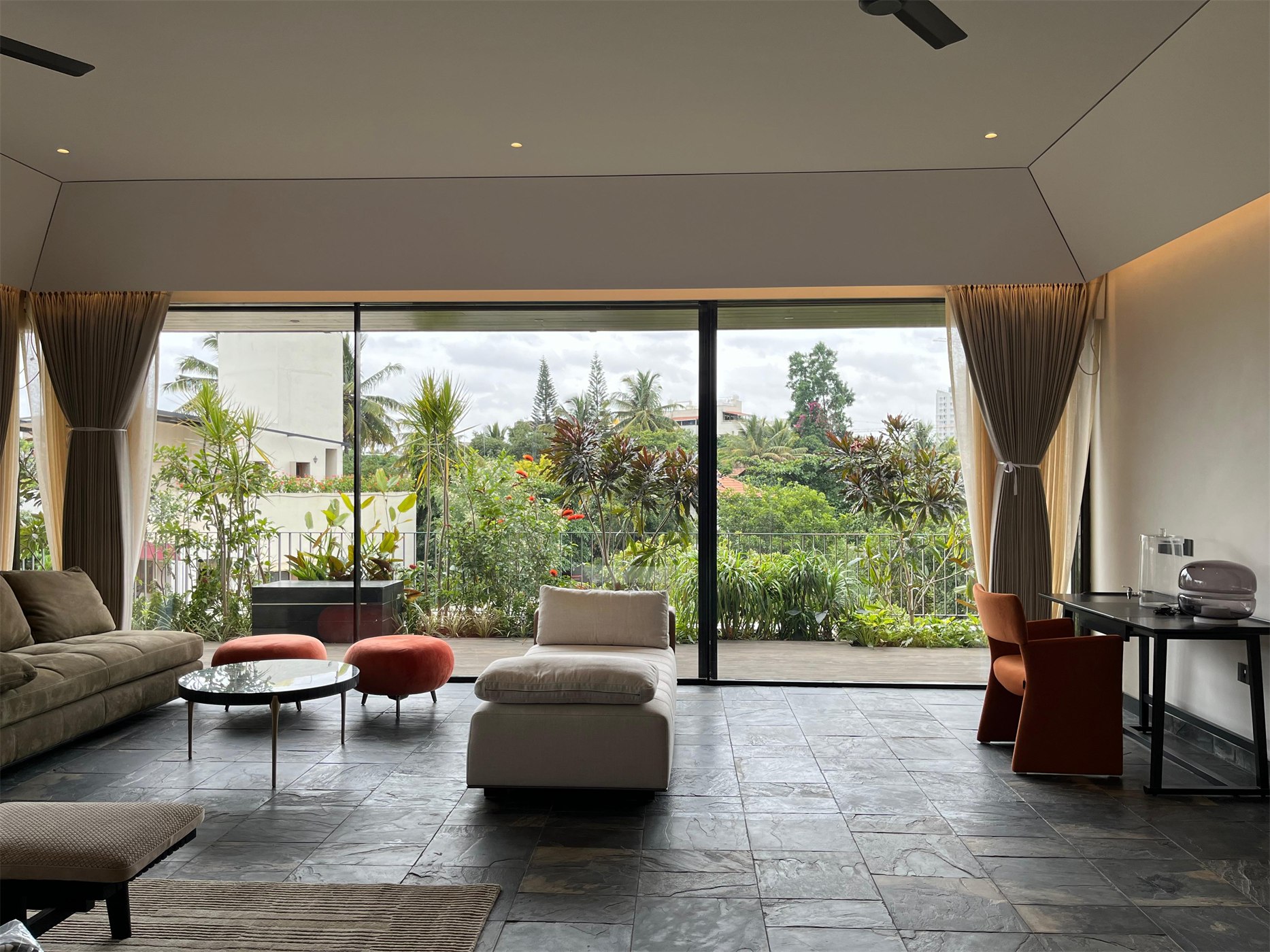 Living room at The Stepped Haven opening onto a planted terrace through full-height sliding glass