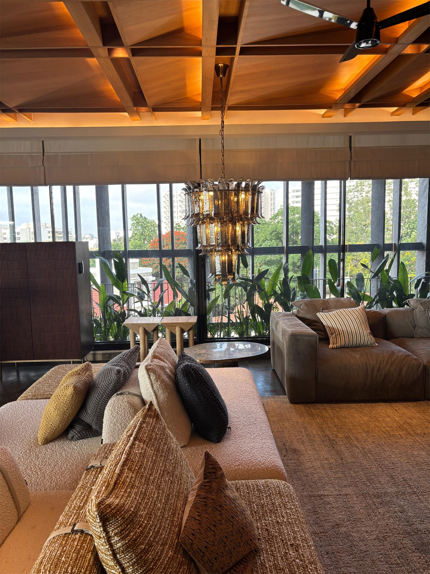 Lounge at The Stepped Haven under a coffered timber ceiling, with a smoked glass chandelier and planted balcony beyond