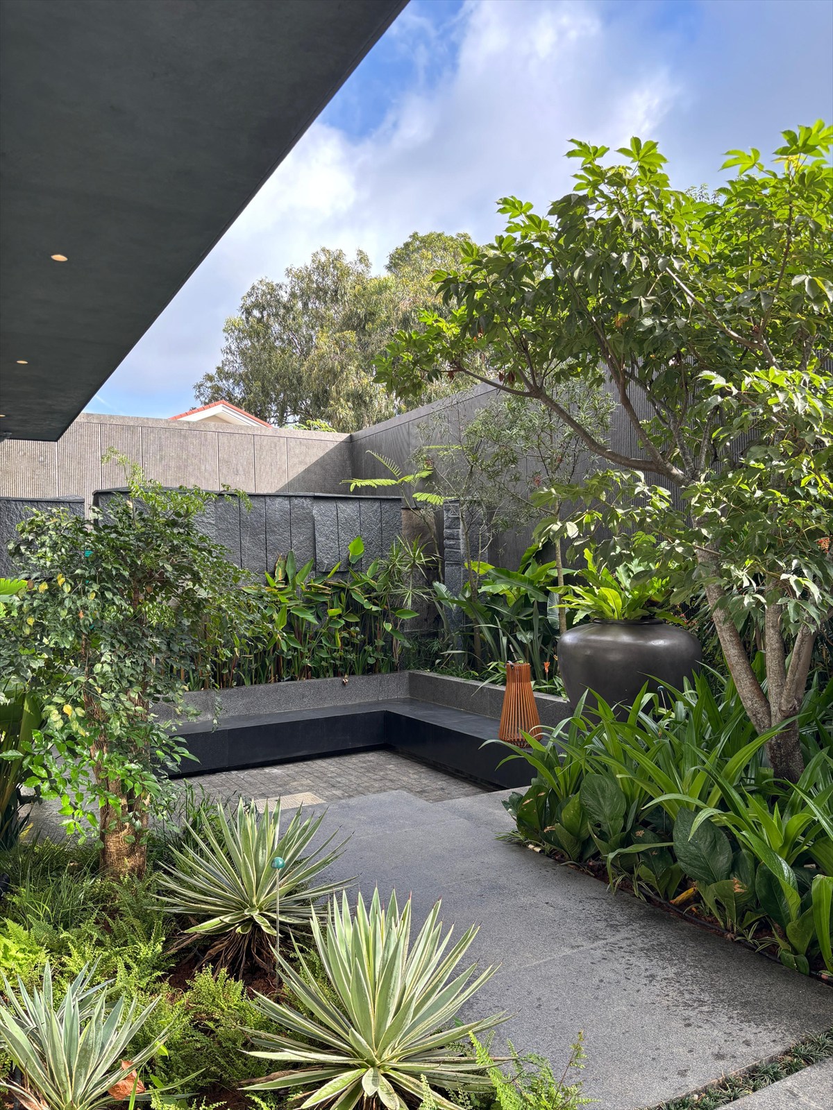 Sunken seating court at The Stepped Haven framed by agaves, tropical planting and a stone wall