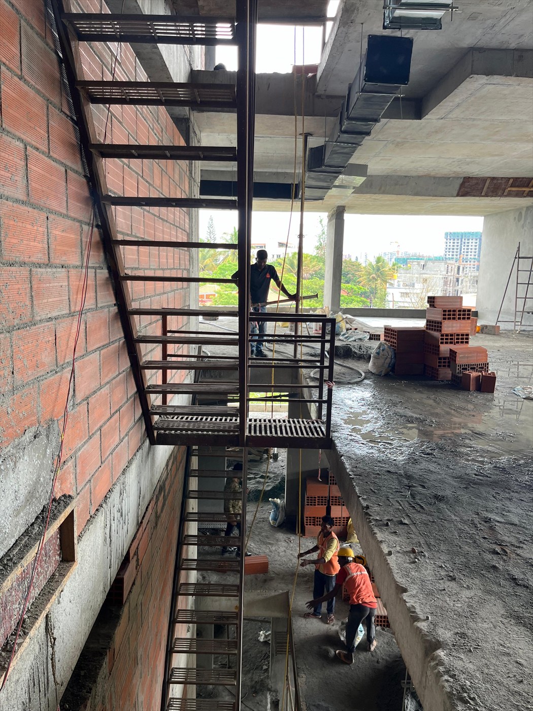 Steel staircase being installed against the brick wall inside The Stepped Haven during construction